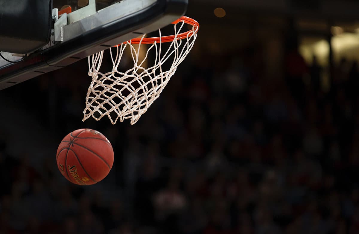 Basketball dropping through a hoop net in an arena
